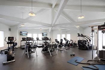 a gym with weights and other exercise equipment in a room with windows